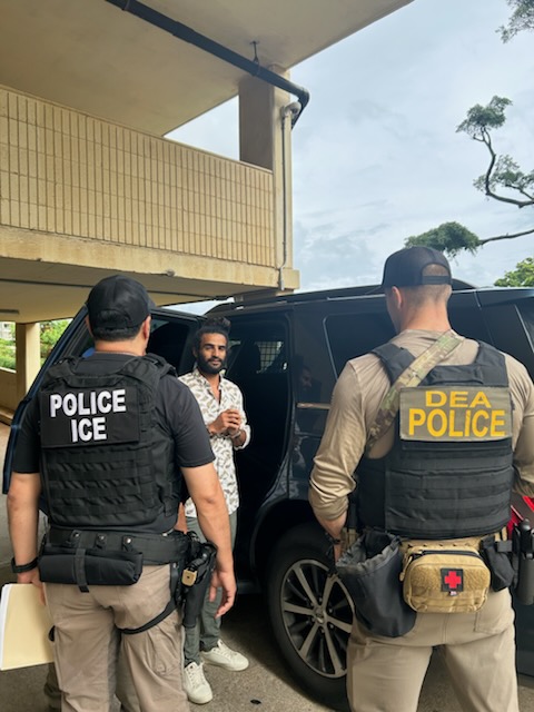 An ICE officer and DEA law enforcement official take an alien into custody during an enhanced immigration enforcement operation Jan. 26.