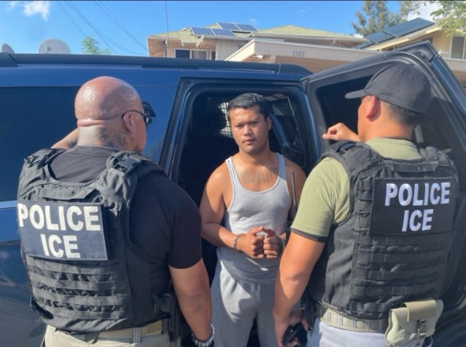 Two ICE officials take an alien into custody during a targeted enforcement operation in Honolulu Jan. 26.