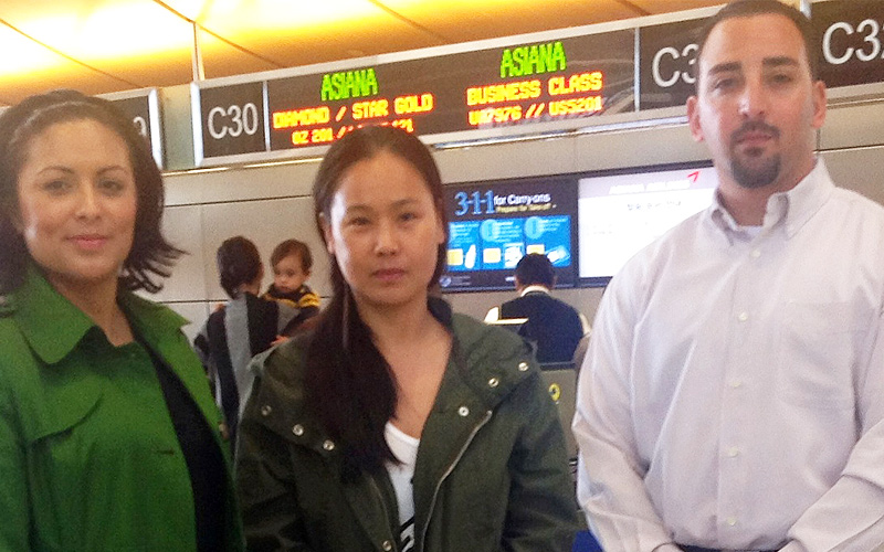 Flanked by ERO escorts, South Korean woman wanted in her native country on prostitution charges prepares to depart LAX.