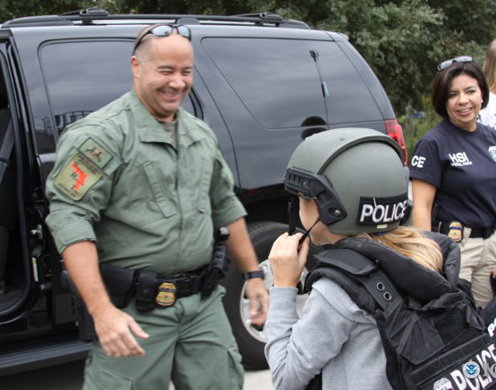 Special Agent Carlos Carrasquillo shows a child in the Tampa Bay region some of the gear worn by U.S. Immigration and Customs Enforcement's (ICE) Homeland Security Investigations (HSI) agents.