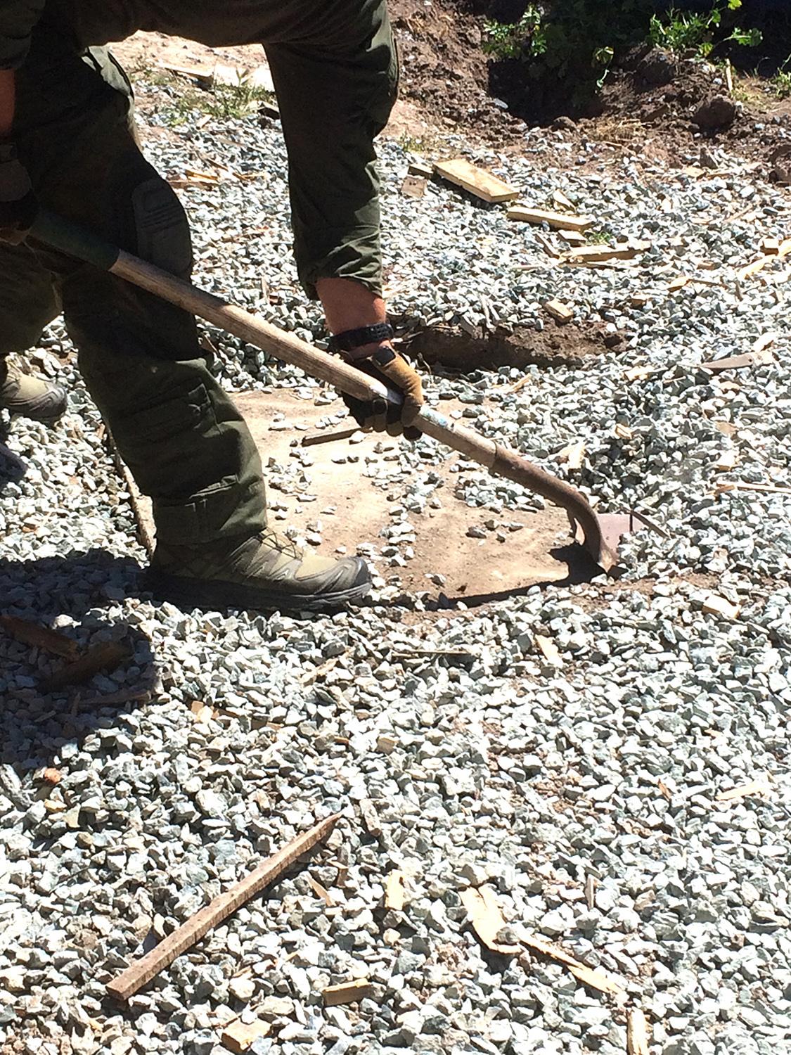 Agent clears rocks away from a wood plank covering the tunnel opening